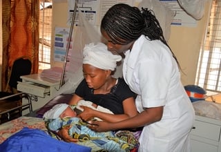 A midwife assists a mother with breast feeding her newborn baby at Princess Christian Maternity Hospital, Freetown
